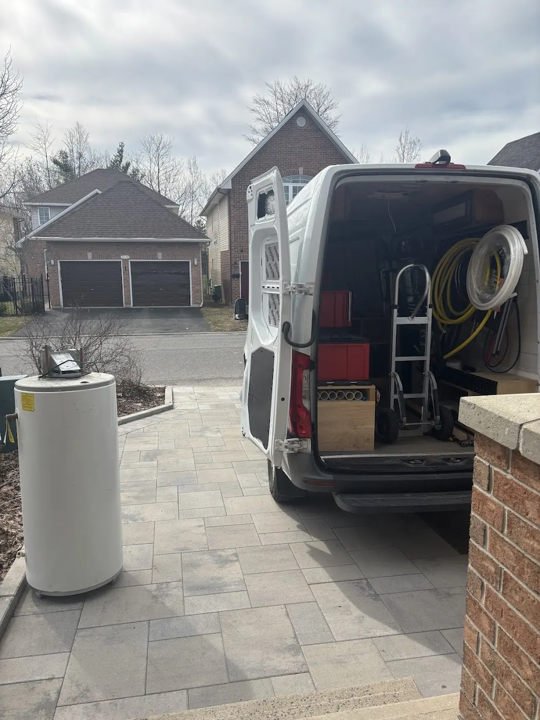 Service van open with tools and a water heater on the driveway